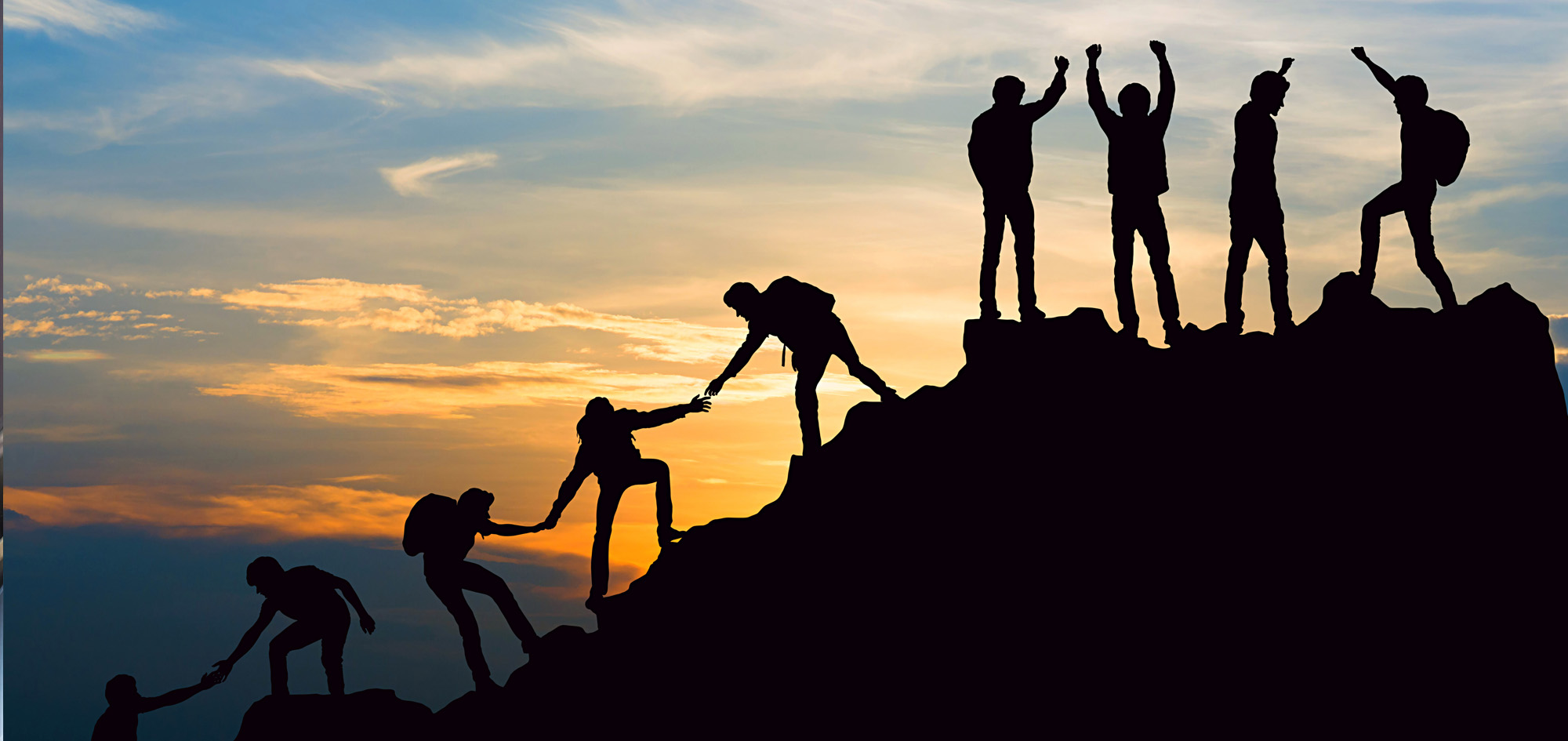 Group of people helping each other to climb a mountain